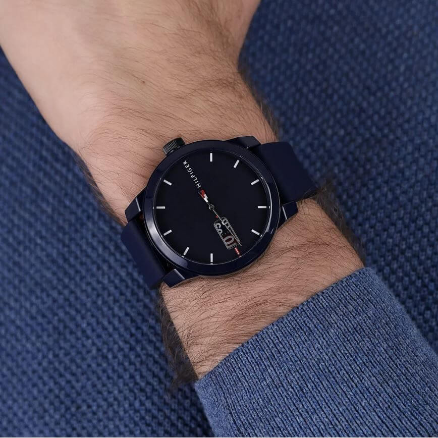 Gent wearing TOMMY HILFIGER Mod. 1791381 quartz analog watch with blue strap and 42mm case, water resistant up to 5 ATM.