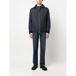 Man wearing Emporio Armani Coats Blue: navy jacket with monogram, silver hardware, drawstring hood, and zip fastening.