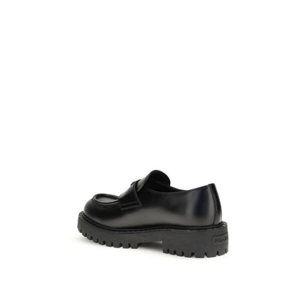 Prada Black Calf Leather Bos Taurus Slip-On Loafers with rubber sole, side view showing craftsmanship and enameled metal triangle detail.