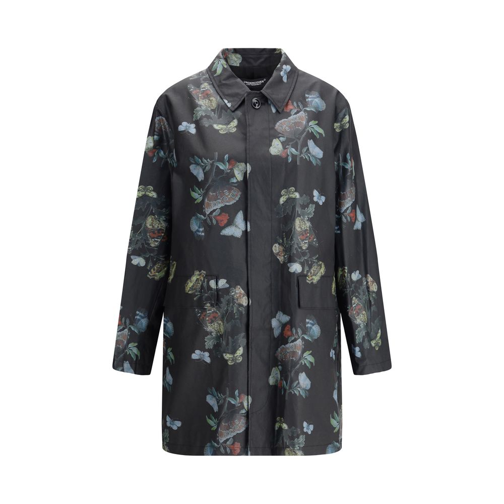 Undercover Black Cotton Coat with floral pattern, front view. Waxed cotton raincoat with flap pockets and cotton lining, AW25 collection.