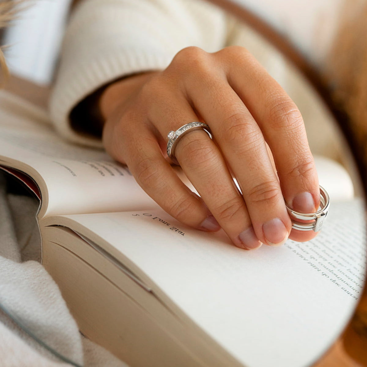 Hand wearing AN JEWELS JEWELRY Mod. AR.R1NS01SC-9 rings while reading a book, showcasing elegant accessory style