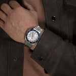 Gent wearing SEIKO 5 Mod. SPORTS AUTOMATIC GMT - WHITE wristwatch with 42mm stainless steel case and bracelet, featuring a water resistance of 10 ATM.