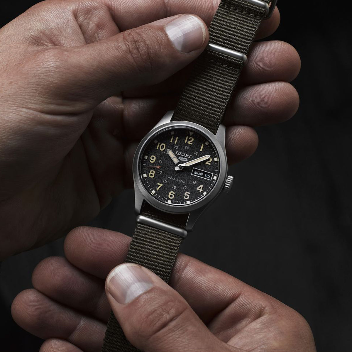 SEIKO MOD. SRPJ85K1 unisex wristwatch with stainless steel case and fabric strap, showing day and date functions on black dial.