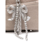 Close-up of silver-tone bow detailing on Self-Portrait suede baguette shoulder bag in grey with zip fastening and suede texture.
