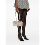 Model holding a Self-Portrait suede baguette shoulder bag with silver-tone hardware and bow detailing, styled with lace tights.