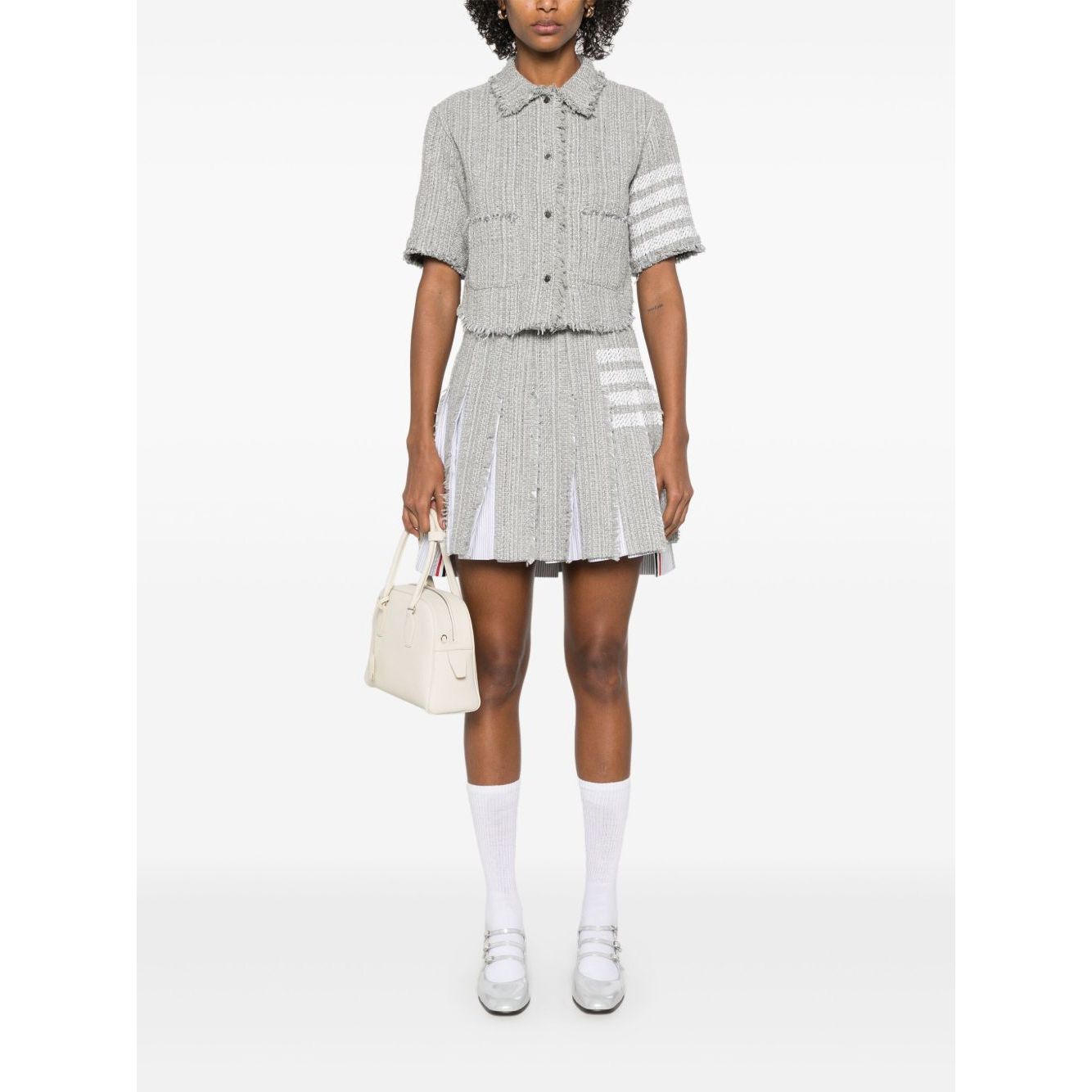 Model wearing Thom Browne Skirts Grey with side button and zip, frayed edge, 4-Bar tab stripe, and cotton blend design.
