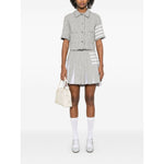 Model wearing Thom Browne Skirts Grey with side button and zip, frayed edge, 4-Bar tab stripe, and cotton blend design.