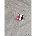 Close-up of grey Thom Browne Trousers featuring signature grosgrain loop tab with 4-Bar stripe, showing cotton texture and drawstring waist detail.