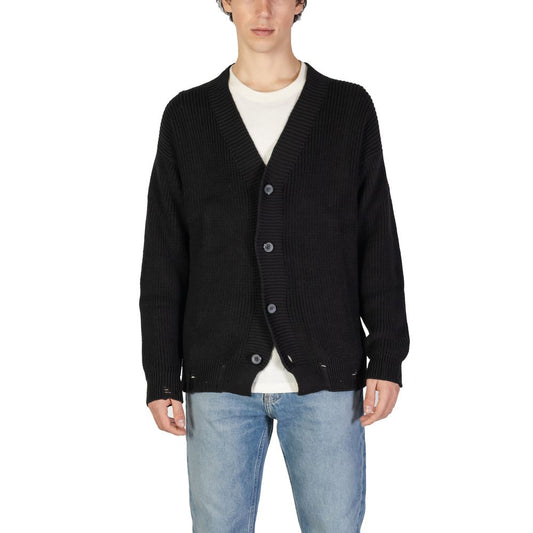 Man wearing Underclub Black Cotton Cardigan with ribbed texture, V-neckline, and large buttons over a white shirt and jeans.