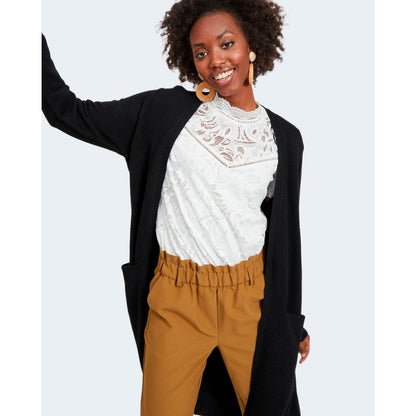Woman wearing Vila Clothes Black Viscose Cardigan with long sleeves, white lace top, and mustard pants.